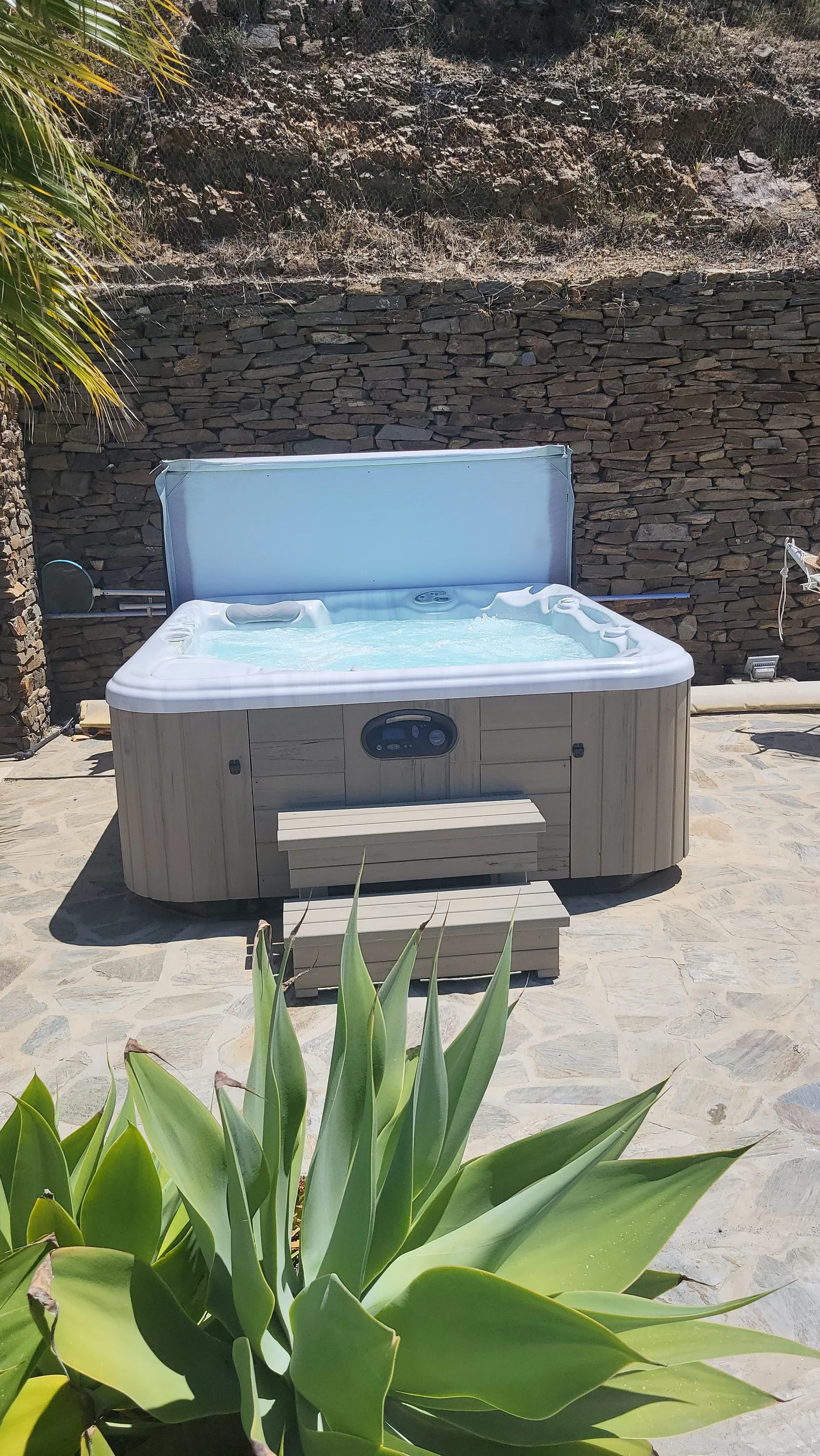 Private jacuzzi with steps beside the stone wall